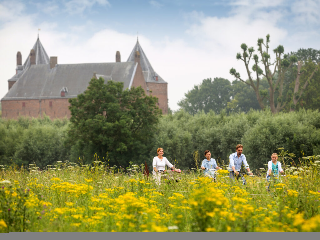 fietsende mensen door de polder bij een kasteel