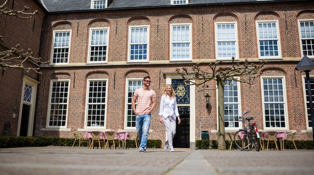 Man en vrouw lopen voor het Museum Elisabeth Weeshuis