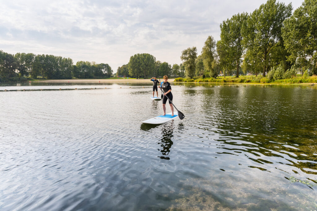 Twee mensen suppen op het water bij de Zandmeren