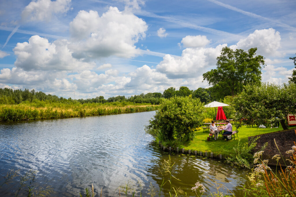 Mensen picknicken langs het water in de Betuwe