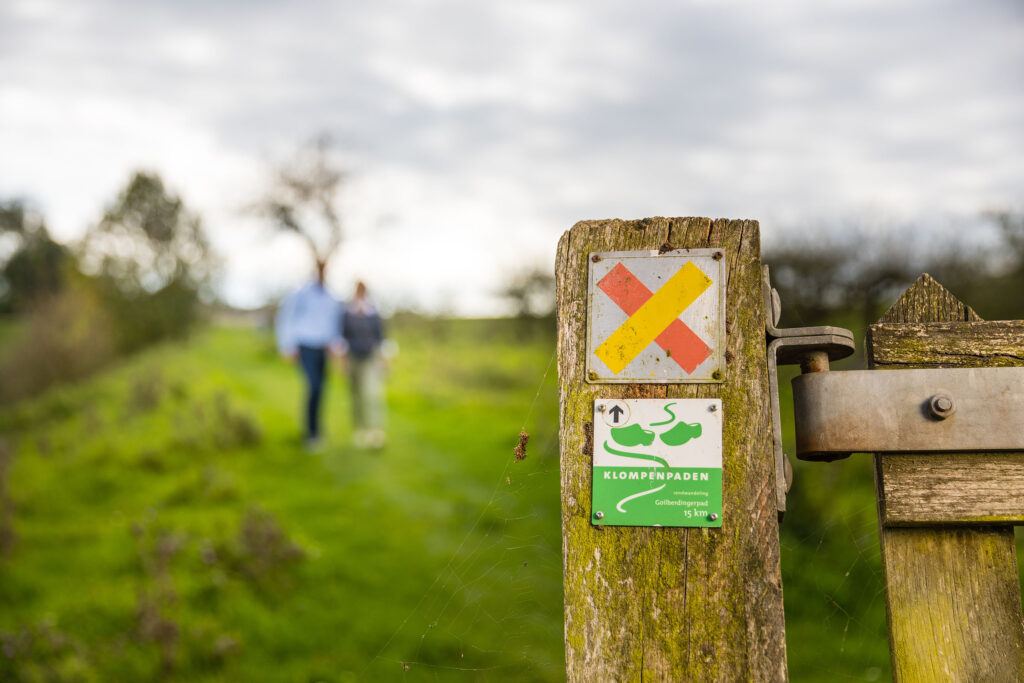 Mensen in weiland bij paaltje klompenpaden wandelroute